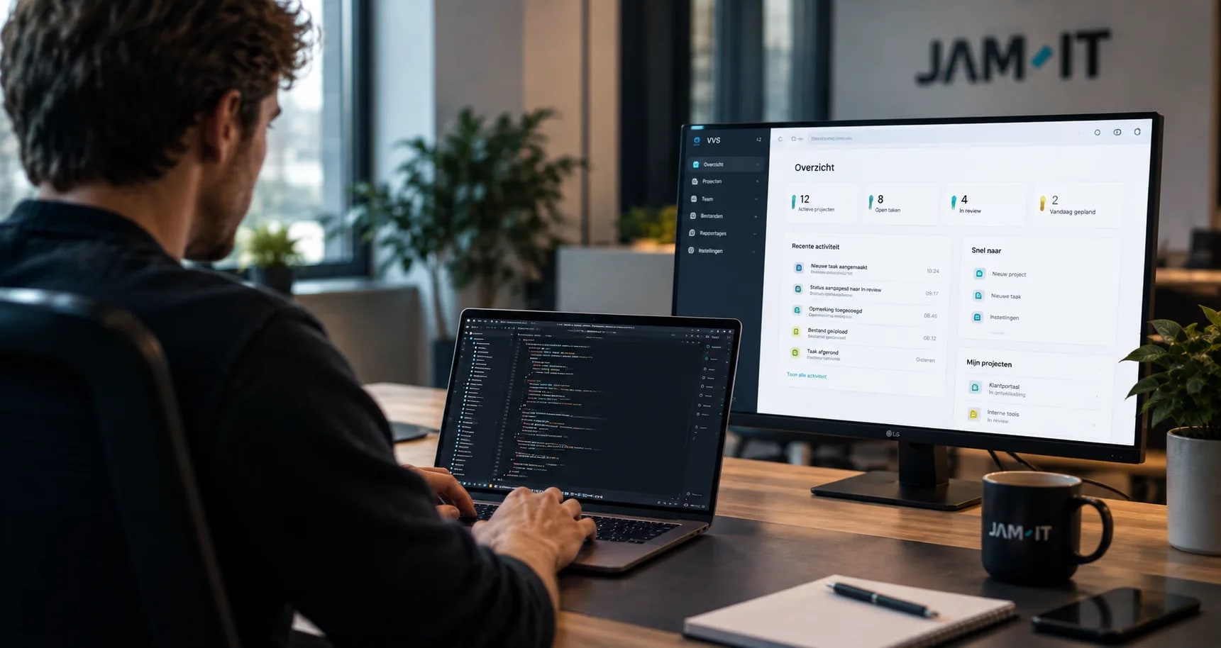 Developer werkt aan een laptop naast een dashboard voor VVS in een JAM-IT kantooromgeving.