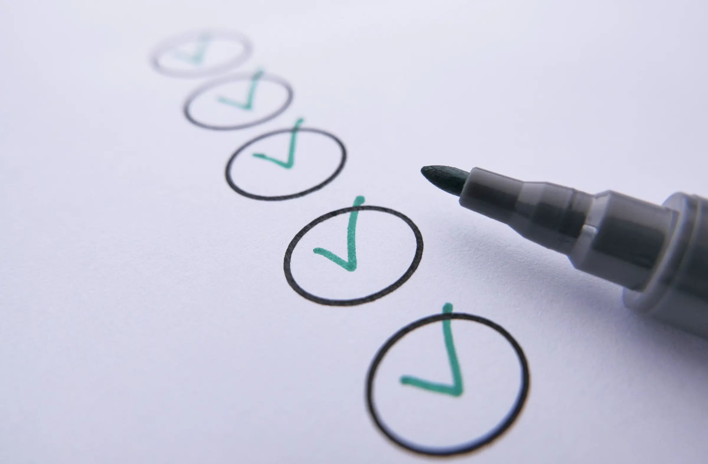 Een checklist waarop vinkjes met groene stift zijn gezet, met de stift ernaast